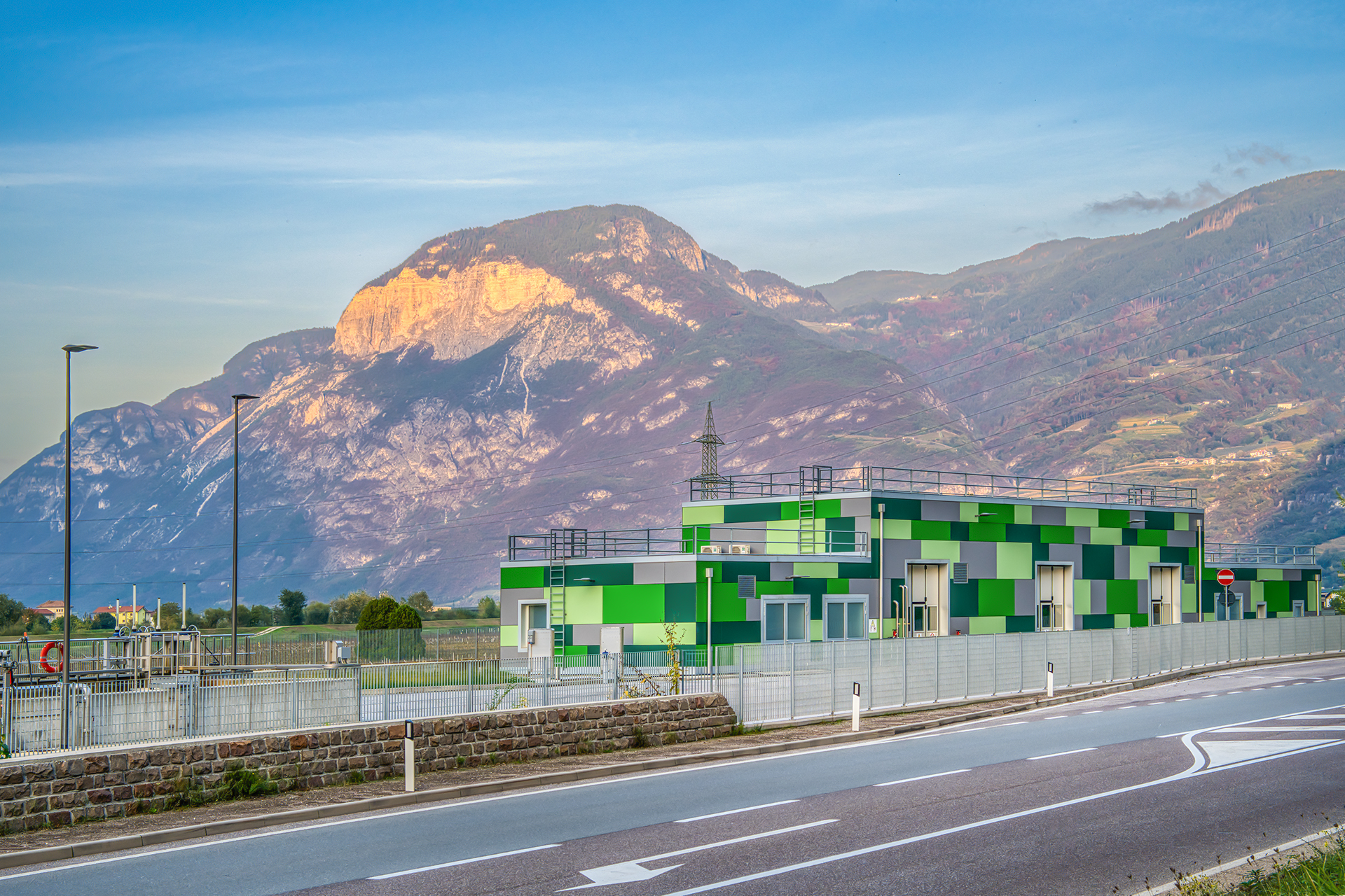 Moderno depuratore di Salorno con pareti verdi, immerso nel paesaggio montano dell'Alto Adige sotto un cielo sereno