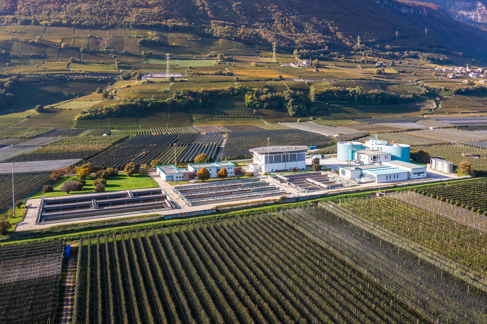 Veduta aerea del depuratore di Termeno, un impianto Eco Center immerso in ampi campi verdi sotto un cielo sereno